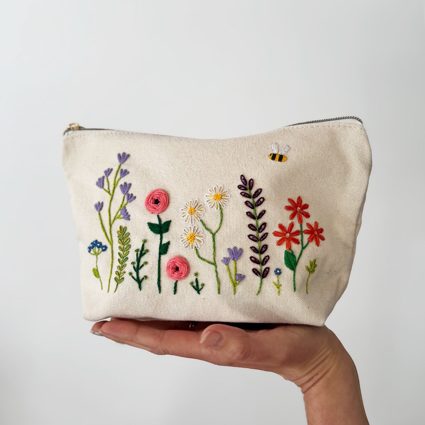 Patchwork with Busyfingers floral embroidery kit on a canvas pouch with flowers and a bee design.