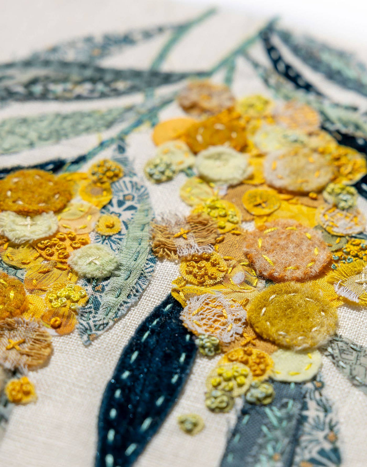 Close-up of Patchwork with Busyfingers Wattle Glow slow stitching kit featuring textured yellow floral fabric applique