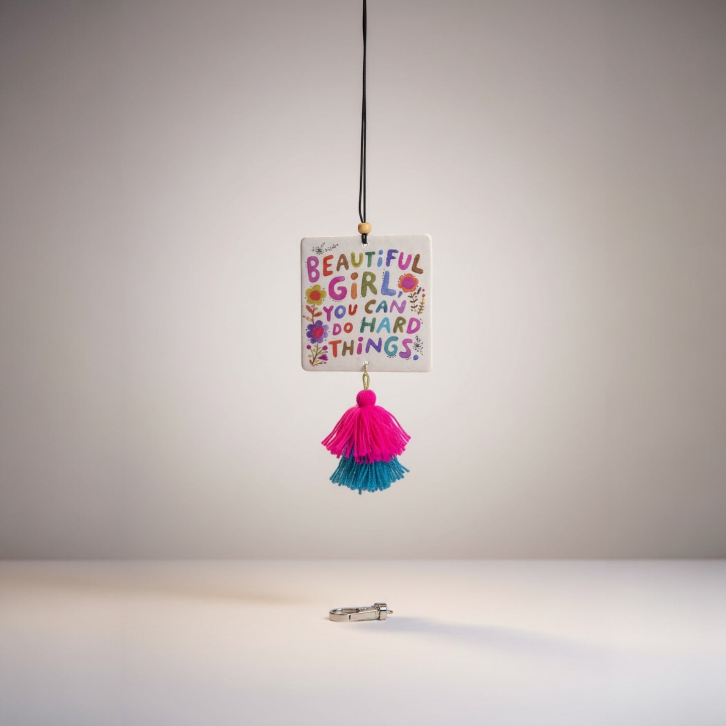Patchwork with Busyfingers air freshener with colorful text 'Beautiful Girl, You Can Do Hard Things' and pink and teal tassels.