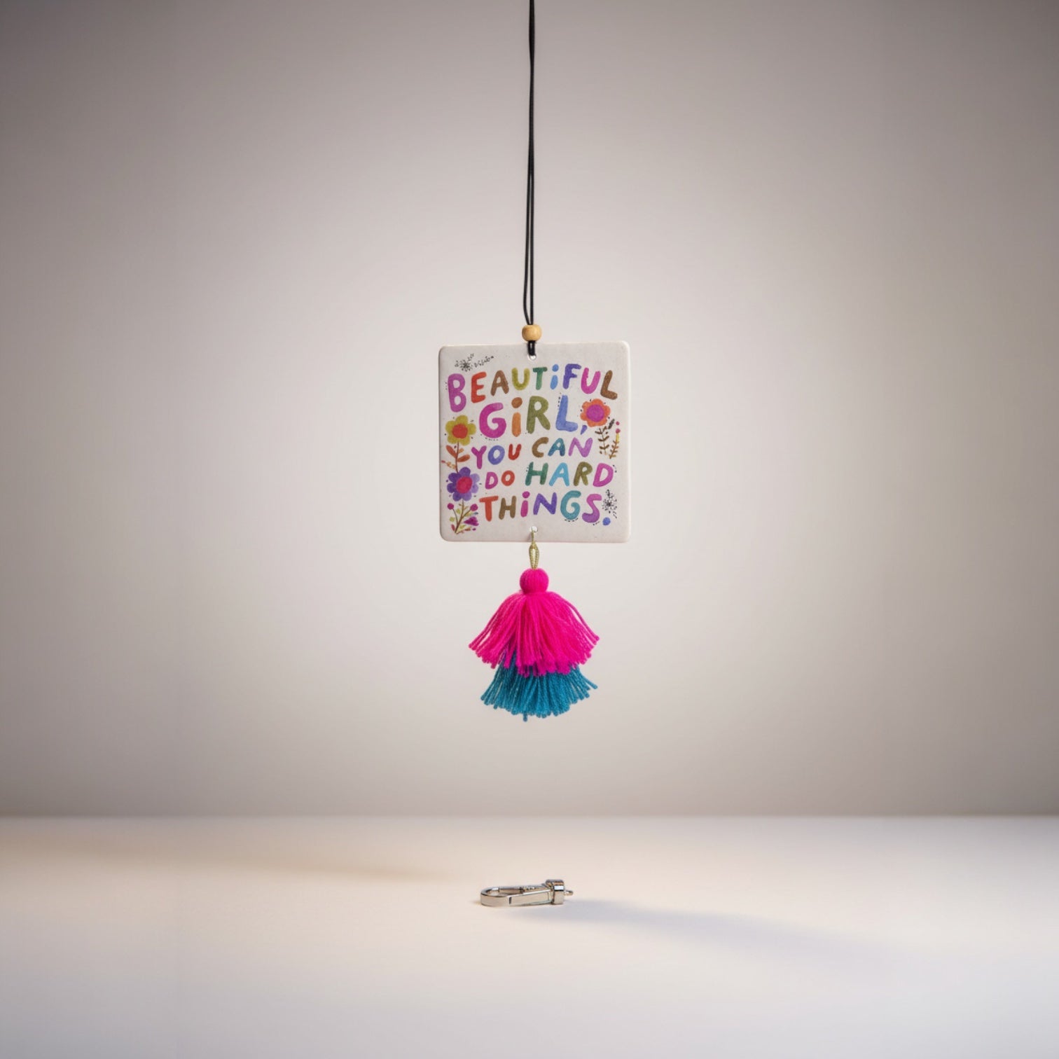 Patchwork with Busyfingers air freshener with colorful text 'Beautiful Girl, You Can Do Hard Things' and pink and teal tassels.