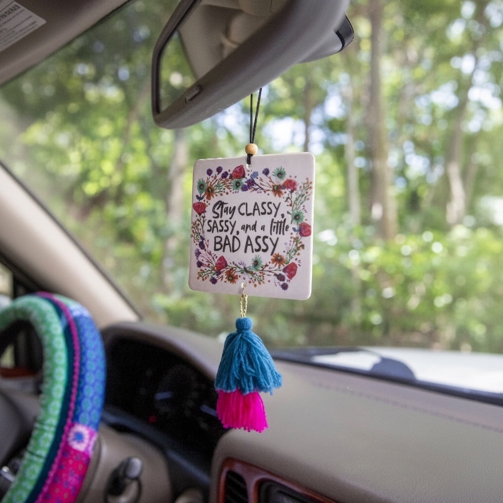 Patchwork with Busyfingers square air freshener with floral border and text 'Stay Classy, Sassy, and a little BAD ASSY'. Features a blue and pink tassel.