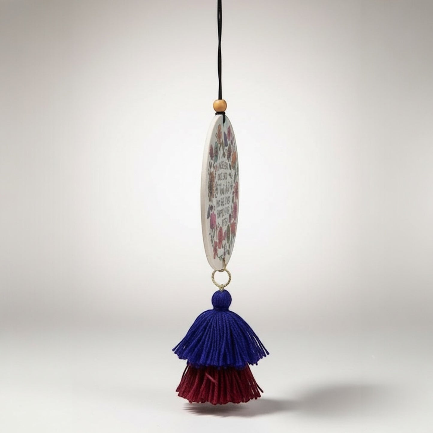 Patchwork with Busyfingers oval air freshener with floral print and quote, featuring blue and burgundy tassels.