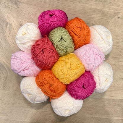 Patchwork with Busyfingers Blushing Stone wool yarn set in white, petal pink, lipstick pink, beige, musk green, rock grey, and stone.