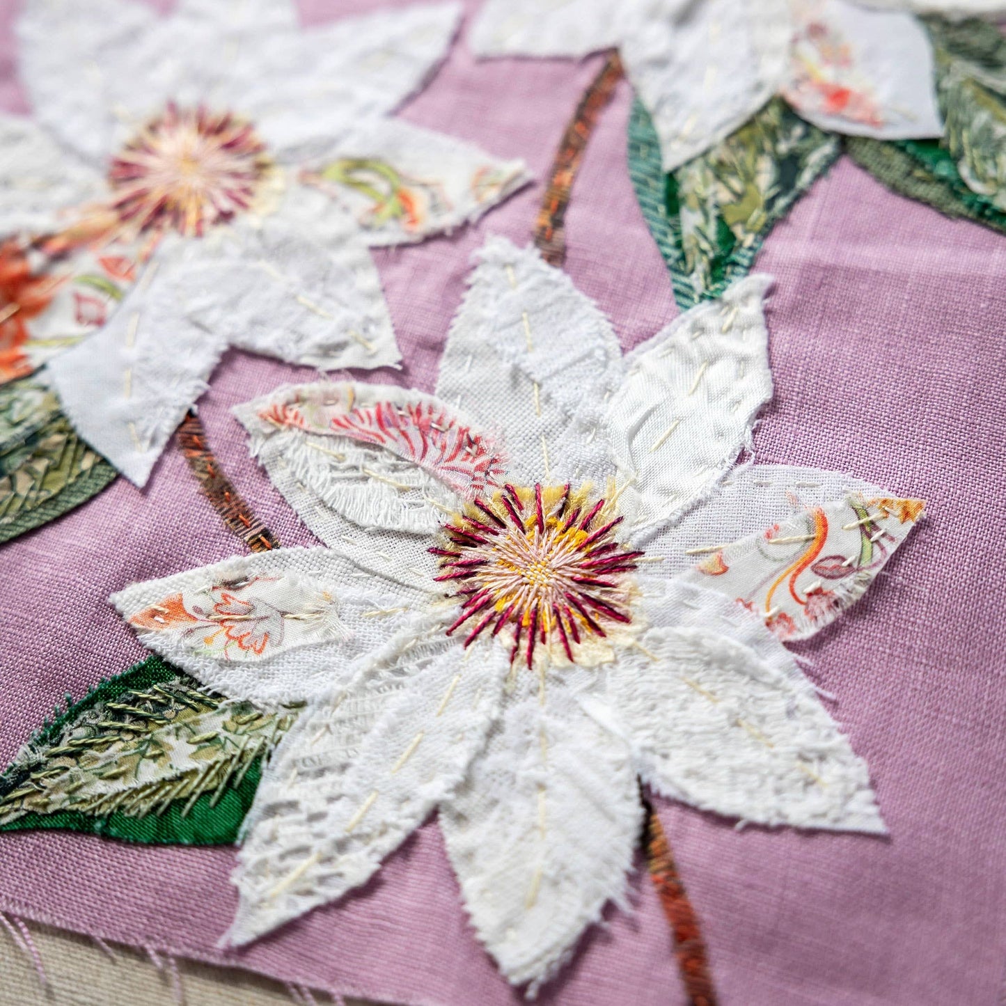 Patchwork with Busyfingers Clematis slow stitching kit featuring white fabric flowers on a pastel purple linen base.
