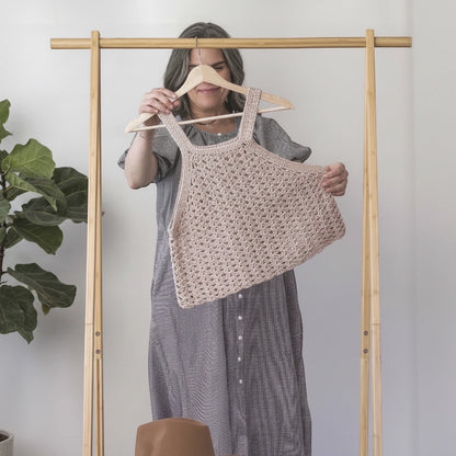 Woman holding a beige crochet tank top from the Patchwork with Busyfingers book Crochet Layers to Love.