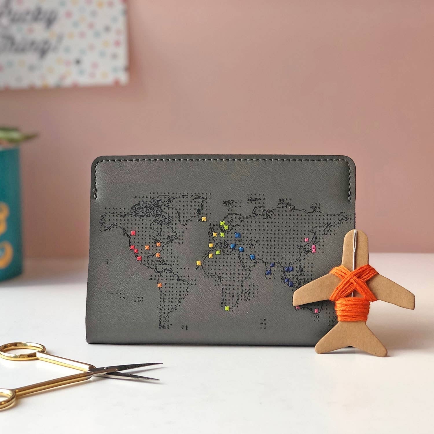 Patchwork with Busyfingers grey faux leather passport holder with embroidered world map, customizable with colorful threads. Features a small airplane embroidery kit.