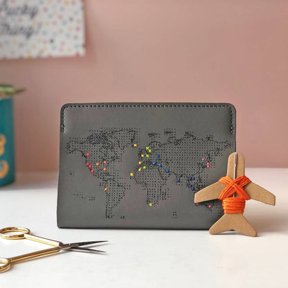 Patchwork with Busyfingers grey faux leather passport holder with embroidered world map, customizable with colorful threads. Features a small airplane embroidery kit.