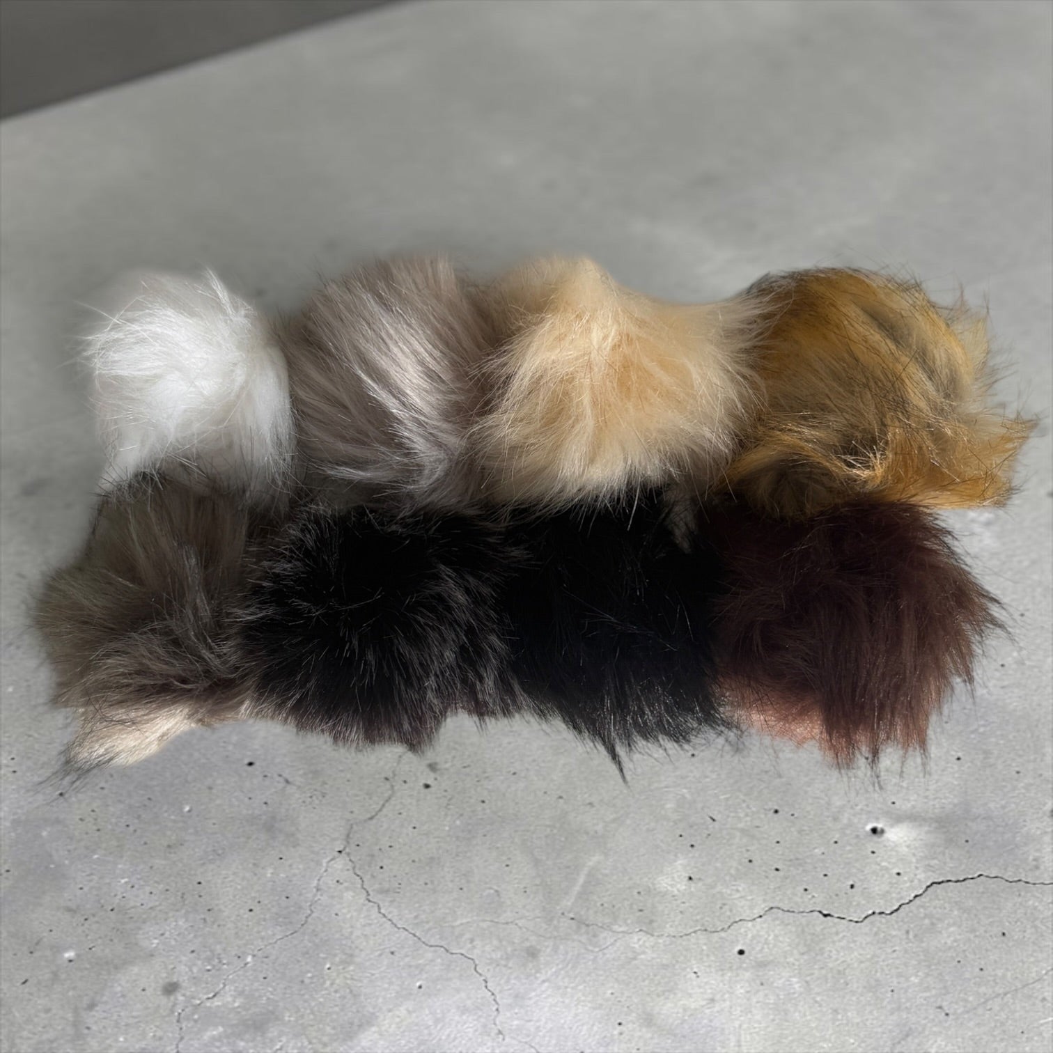 Patchwork with Busyfingers plush faux fur beanie pom poms in a variety of natural brown, black, and white shades.