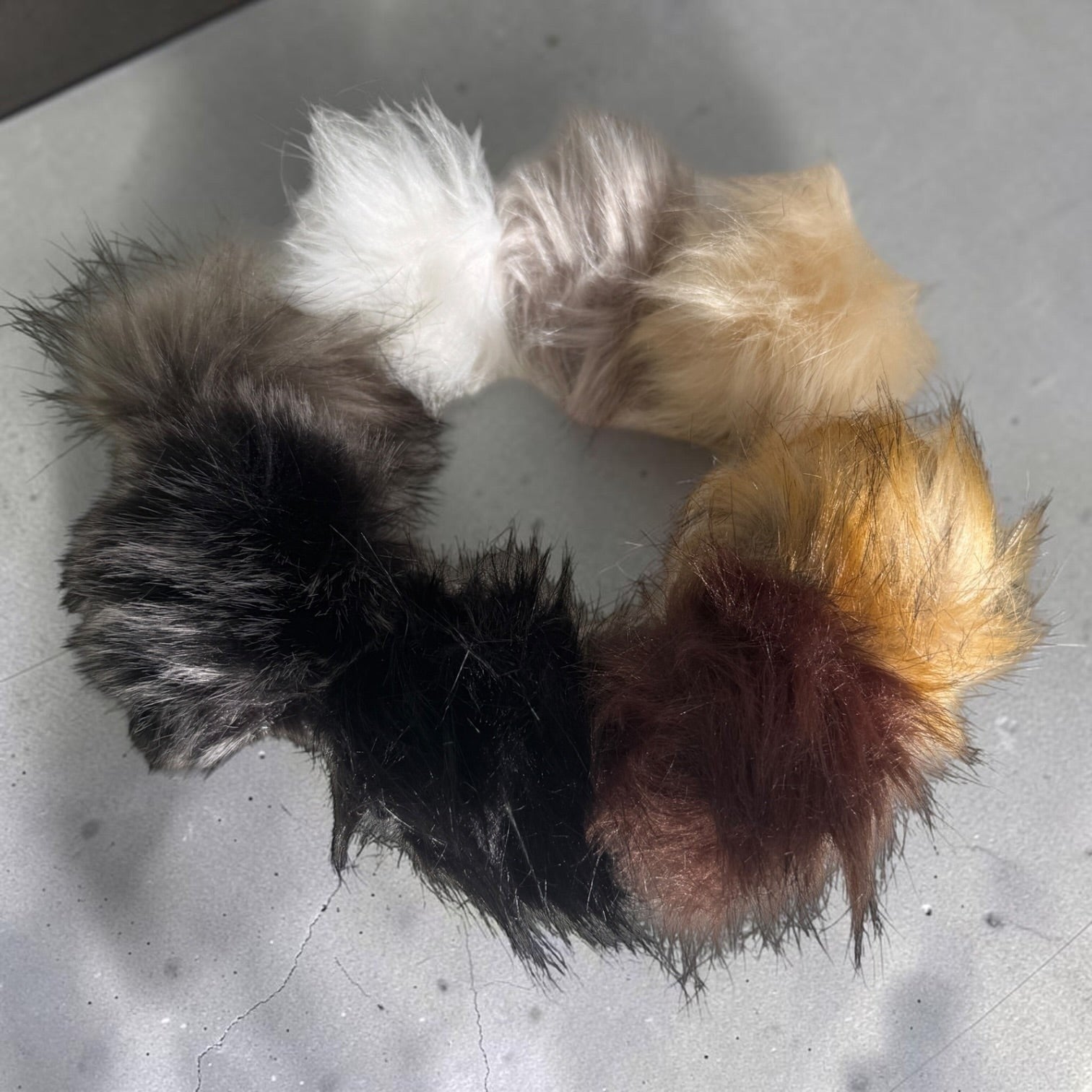Patchwork with Busyfingers plush faux fur beanie pom poms in a circular arrangement of assorted natural colours