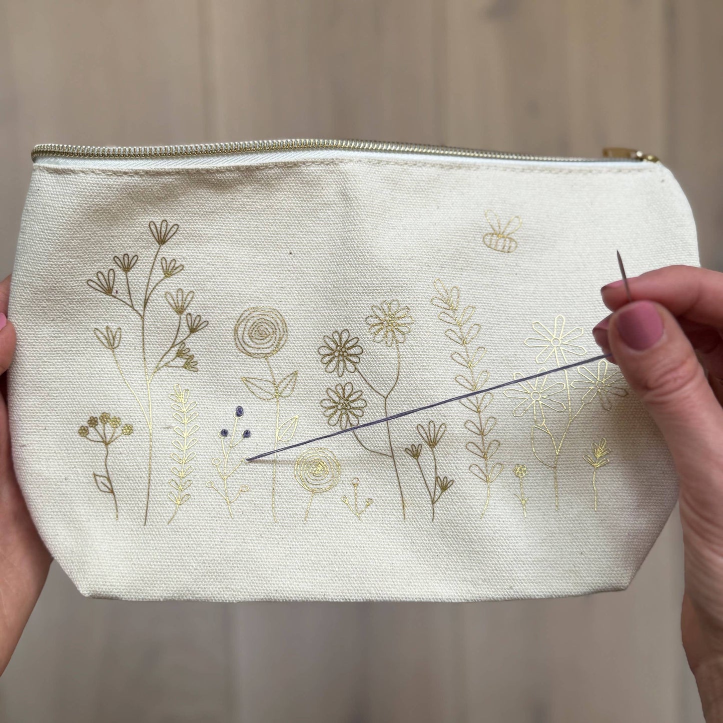 Patchwork with Busyfingers floral embroidery kit on a canvas pouch with gold thread flowers and a bee design.