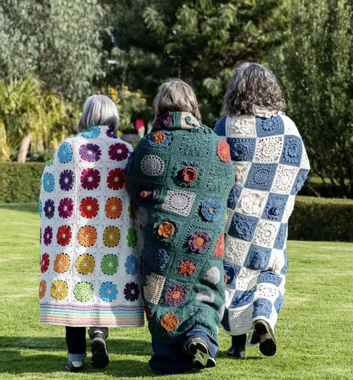 Three people walking outdoors wearing Patchwork with Busyfingers Granny Square Garden crochet blankets