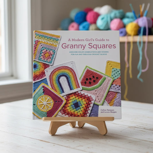 Patchwork with Busyfingers A Modern Girl’s Guide to Granny Squares book on a wooden stand with colorful yarn balls