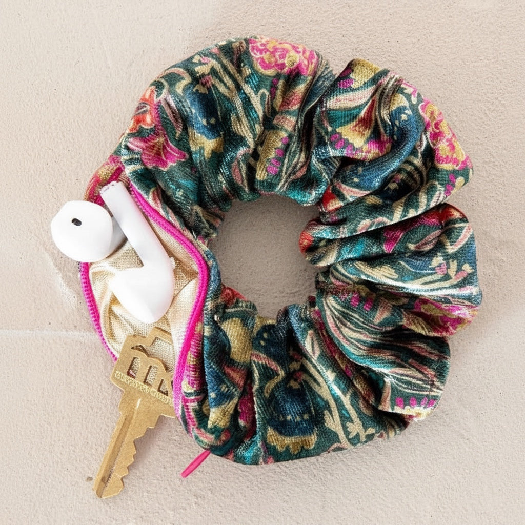 Patchwork with Busyfingers green floral velvet scrunchie with hidden zipper compartment holding earbuds and a key.