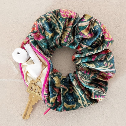 Patchwork with Busyfingers green floral velvet scrunchie with hidden zipper compartment holding earbuds and a key.