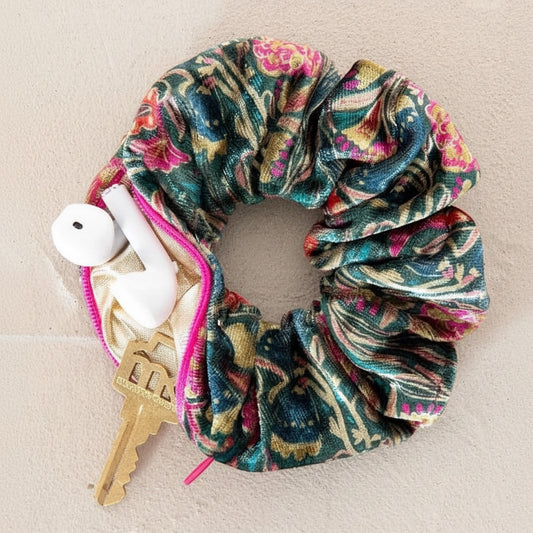 Patchwork with Busyfingers green floral velvet scrunchie with hidden zipper compartment holding earbuds and a key.