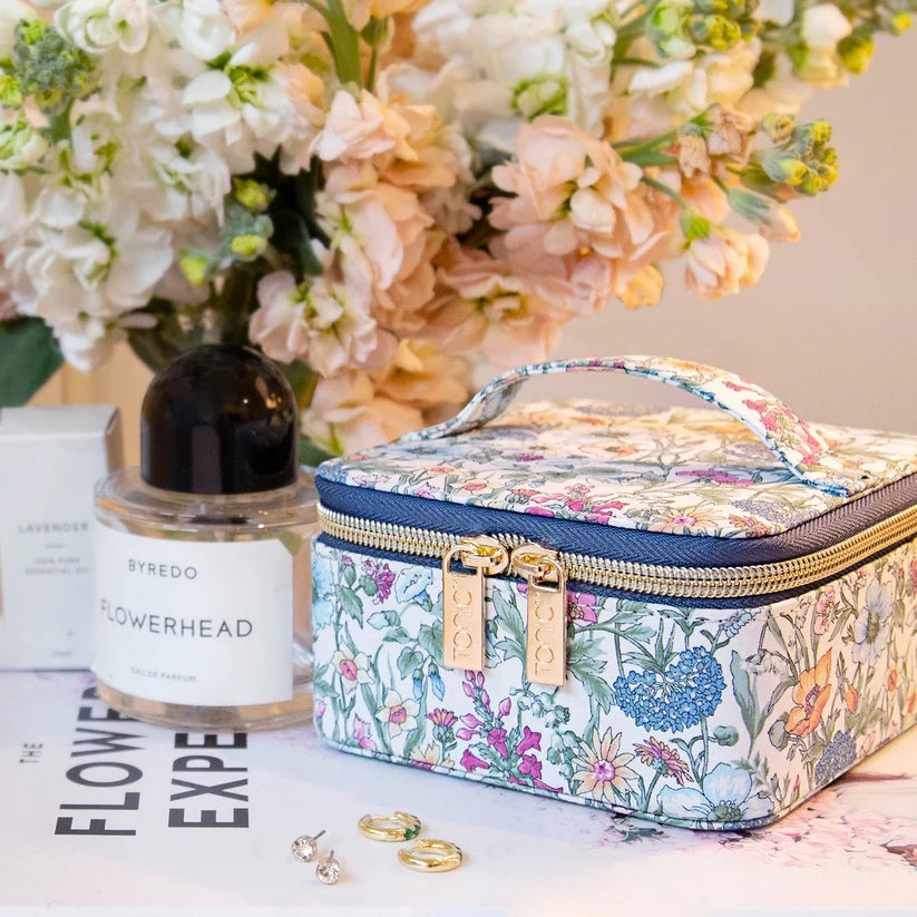 Patchwork with Busyfingers small floral print jewellery cube with navy trim and gold zippers, next to perfume and earrings.