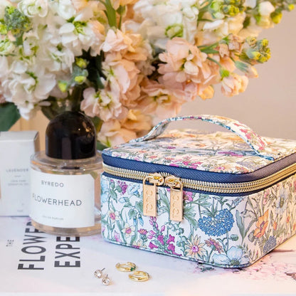 Patchwork with Busyfingers small floral print jewellery cube with navy trim and gold zippers, next to perfume and earrings.