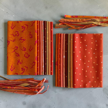 Patchwork with Busyfingers Marigold Spice 8-piece cotton fabric fat eighth pack in assorted orange and red prints.