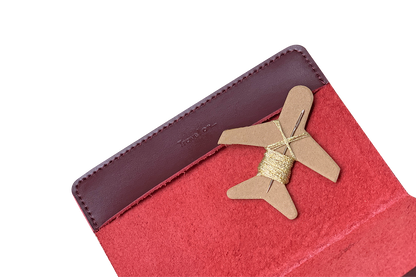 Patchwork with Busyfingers maroon leather passport cover kit with red suede interior and airplane-shaped embroidery floss holder.