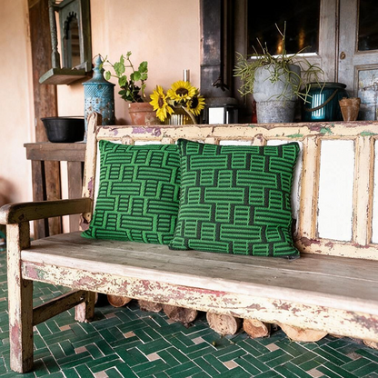 Two green and black mosaic crochet pillows from Patchwork with Busyfingers displayed on a rustic wooden bench.