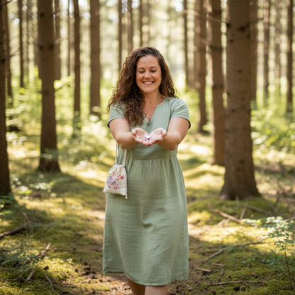 Patchwork with Busyfingers Bag of Pocket Tokens with floral design, a hand places a silver heart token on a mossy rock.