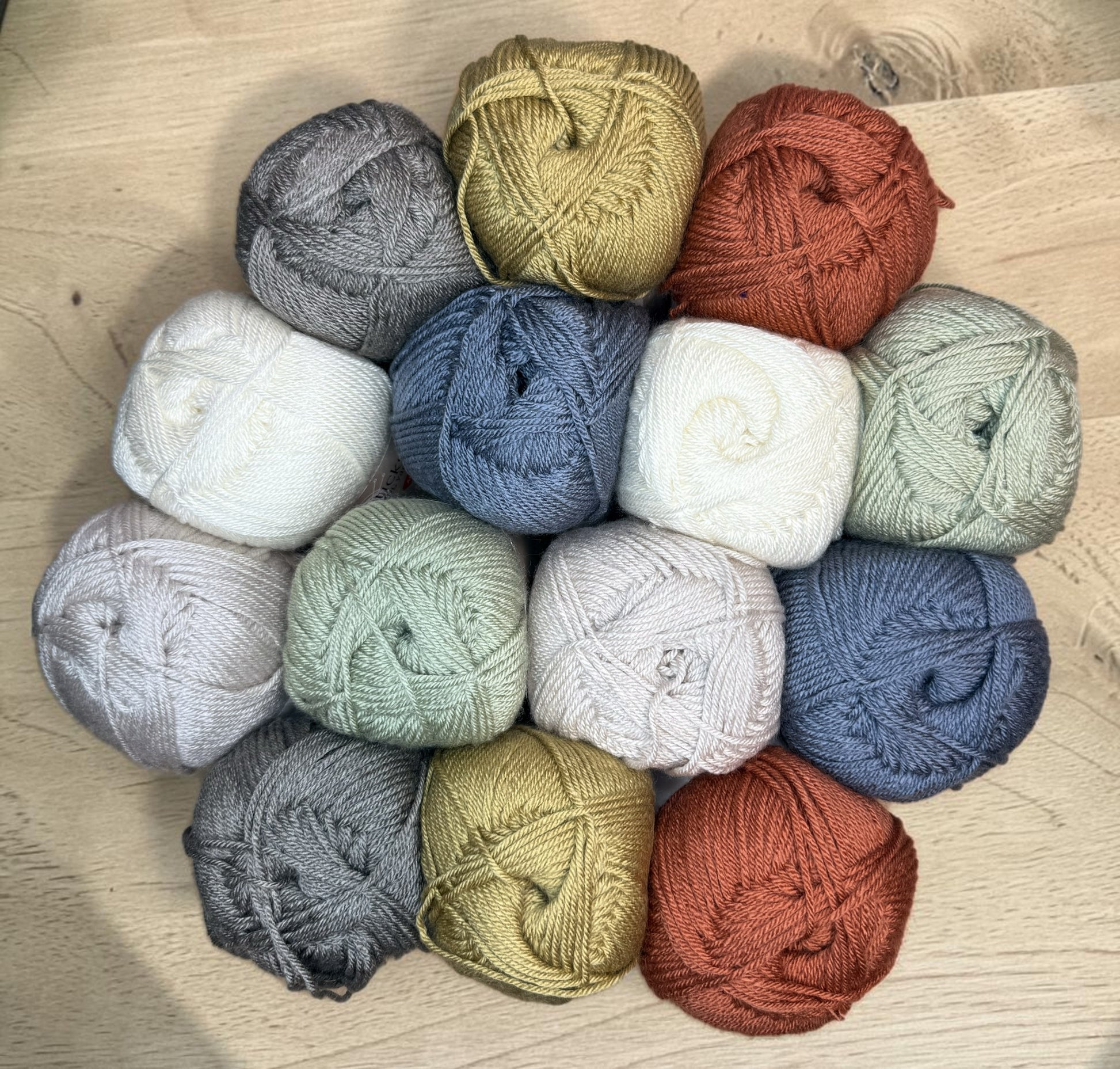 Patchwork with Busyfingers Saltgrass & Clay yarn set in cream, moss, coral, steel blue, grey brown, natural, and tan. 100% anti-pilling acrylic yarn.