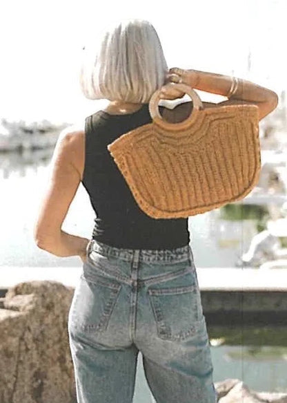 Patchwork with Busyfingers Summer Crochet book inspiration featuring a woman carrying a woven straw bag by the marina