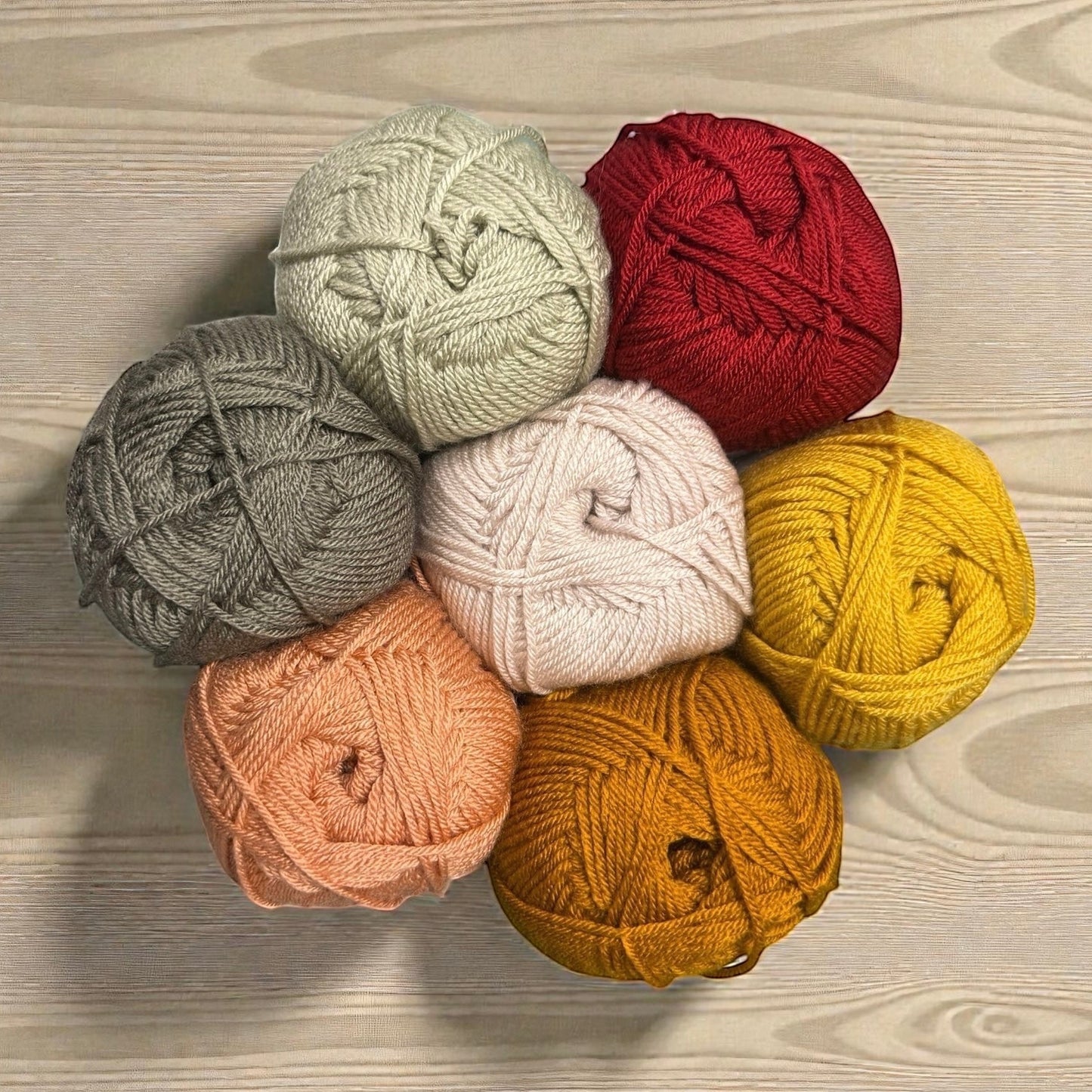 Patchwork with Busyfingers yarn set in red, yellow, mustard, peach, pink, grey, and sage green for The Hidden Stitch Blanket CAL.