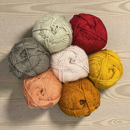 Patchwork with Busyfingers yarn set in red, yellow, mustard, peach, pink, grey, and sage green for The Hidden Stitch Blanket CAL.