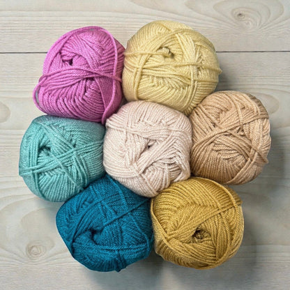 Patchwork with Busyfingers yarn set for The Hidden Stitch Blanket CAL. Includes pink, yellow, cream, tan, teal, and gold yarn balls.