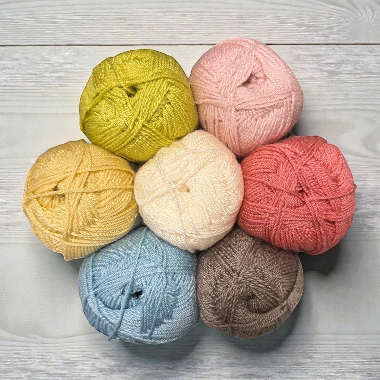 Patchwork with Busyfingers yarn set for The Hidden Stitch Blanket CAL: pale yellow, cream, light blue, brown, lime green, pink, and coral.