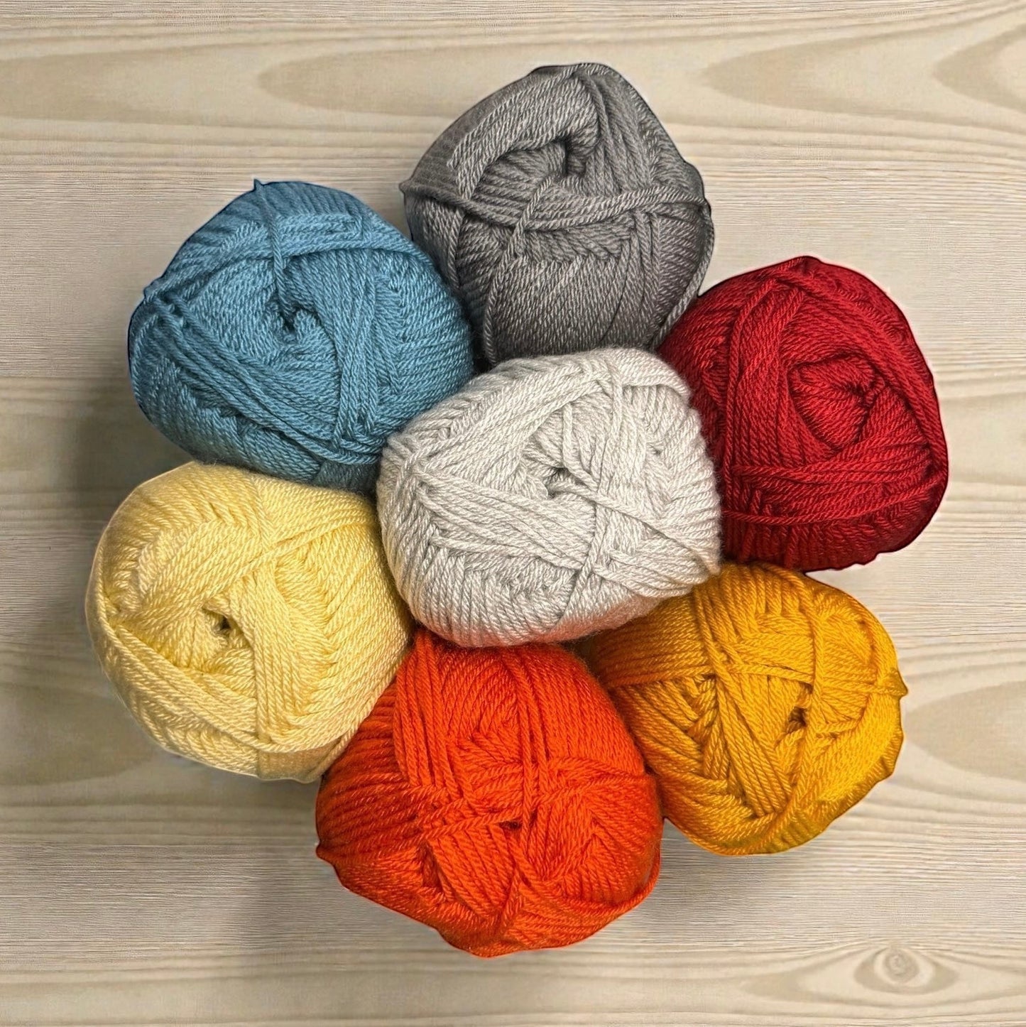 Patchwork with Busyfingers yarn set in red, orange, yellow, light blue, grey, and white for The Hidden Stitch Blanket CAL.