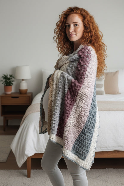 Patchwork with Busyfingers Hidden Stitch yarn set in cream, sand, dusty pink, and grey, draped over a pregnant woman.