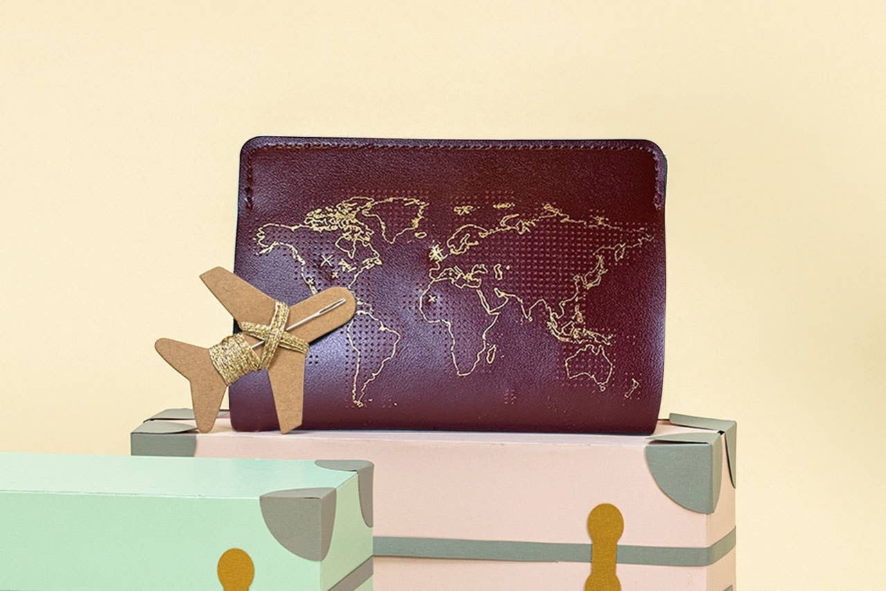 Patchwork with Busyfingers maroon leather passport cover kit with gold world map embroidery and airplane detail.